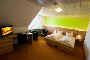 a bedroom with a bed and a desk and a television at Hotel Traube Lossburg in Loßburg
