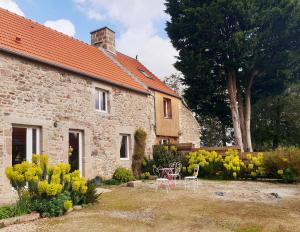 a stone house with chairs and tables in a yard at Le chambre du Clos Giot in Saint-Vaast-la-Hougue