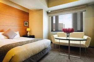 a hotel room with a bed and a table with flowers on it at Citadines Central Shinjuku Tokyo in Tokyo