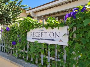 a sign on a fence with purple flowers at Villaggio Mietta in Castiglioncello