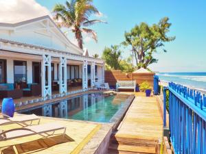 a house with a swimming pool next to the ocean at Villa Victoria in Saint-Gilles les Bains