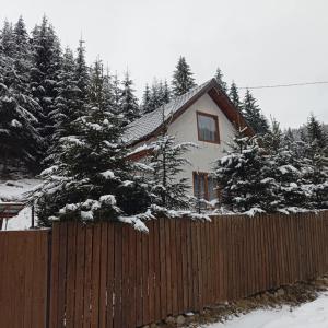 una casa dietro una recinzione con alberi coperti di neve di Csillag kulcsoshaz a Gheorgheni