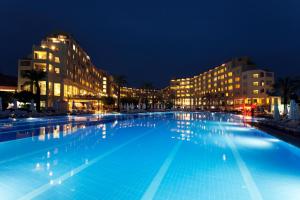 una gran piscina por la noche con edificios en Selectum Family Resort Side, en Kizilagac