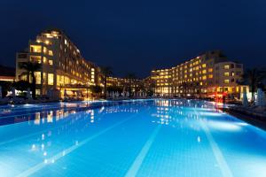 een groot zwembad 's nachts met gebouwen bij Selectum Family Resort Side in Kizilagac