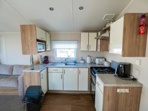 eine kleine Küche mit weißen Schränken und einem Sofa in der Unterkunft North Shore Skegness, 3 Bedroom 2 Bathroom Sleeps 8 in Skegness + 18 Fotos