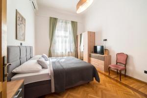 a bedroom with a bed and a tv and a chair at Golden Star Apartment - Spacious City Center Stay in Zagreb