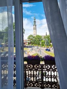 a window with a view of a clock tower at Biały Kruk Apartamenty vis-a-vis Jasnej Góry in Częstochowa