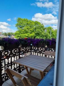 a wooden table and benches on a balcony with flowers at Biały Kruk Apartamenty vis-a-vis Jasnej Góry in Częstochowa