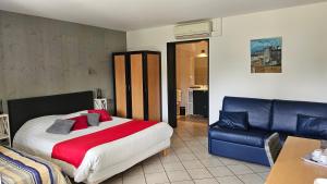 a bedroom with a large bed and a blue leather couch at Résidence Hôtelière La Farguaise 3min du péage in Fargues-de-Langon