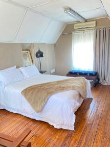 a bedroom with a large white bed with a wooden floor at 2 Bedroom Cottage sleeps maximum 4 Buhlebendalo in Benoni