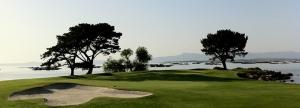 un campo de golf con un verde con árboles y agua en Hotel Amandi, en O Grove