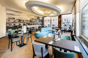 a restaurant with tables and chairs and a chandelier at NH Amsterdam Caransa in Amsterdam