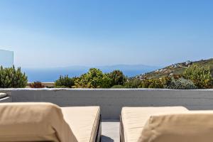 a balcony with chairs and a view of the ocean at Sea Breeze Villa Triantaros Tinos in Triandáros