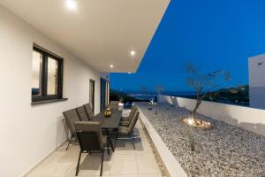 ein Esszimmer mit einem Tisch, Stühlen und einem Baum in der Unterkunft Villa Vista Adriatica in Donji Seget
