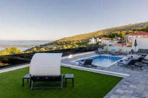 eine Terrasse mit Pool und Stühlen auf dem Rasen in der Unterkunft Villa Vista Adriatica in Donji Seget