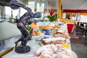 una mesa con una estatua de una persona comiendo pasteles en Hotel del Sole en Pompei