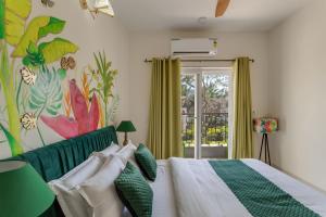 a bedroom with a bed and a painting on the wall at Alaya Stays Cavalo Marinho - 3 BHK Boho Retreat with Private Pool & Terrace in Camorlim