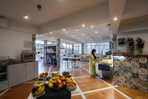 a woman standing in a kitchen with a table of fruit at Amalfi Hotel centro storico in Amalfi