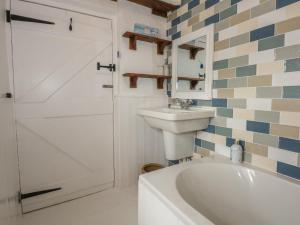 a bathroom with a sink and a tub and a toilet at Melin Rhos Farm in Penrhos-Lligwy