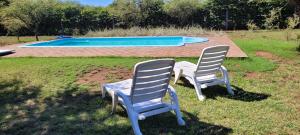 two chairs sitting in the grass near a swimming pool at La Sietecolores in Toay