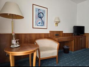 a room with a table and a chair and a lamp at Pension De Lux Königsbrunn in Königsbrunn