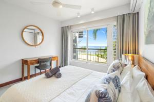 a bedroom with a bed and a desk and a window at Kanope Bay - Holiday Beachfront Apartments in Pointe aux Biches