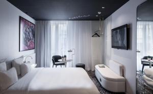 um quarto com uma grande cama branca e uma secretária em Le Général Hôtel em Paris