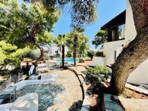 eine Terrasse mit Stühlen, einem Baum und einem Pool in der Unterkunft Villa Pharaoh Private Pool Near the Beach in Porto Rafti