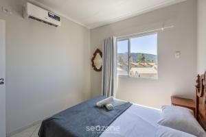 a white bedroom with a bed and a window at Apto Vista Mar 3Q e Garagem 130m da Praia ROR0002 in Bombas