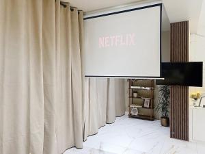 a screen with a netflix sign in a room with curtains at V' Appart SPA Moderne-Chic in Troyes