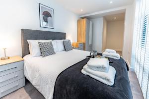 een slaapkamer met een groot bed met handdoeken erop bij Wellington House by Celador Apartments in Reading