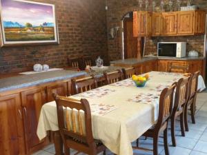 een keuken met een tafel met stoelen en een tafel bij Uitzicht Guest Farm in Kroonstad