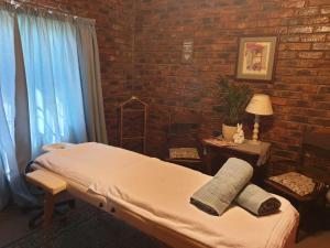 een ziekenhuiskamer met een bed en een bakstenen muur bij Uitzicht Guest Farm in Kroonstad