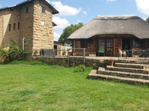 een gebouw met een rieten dak waar twee koeien voor staan bij Uitzicht Guest Farm in Kroonstad