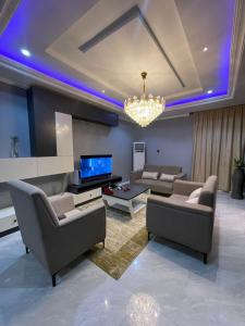 a living room with couches and a television and a chandelier at Four bedrooms fully furnished apartment in Abuja