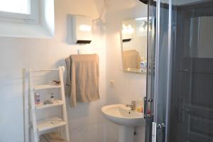 uma casa de banho branca com um lavatório e um chuveiro em Petit Paris em Kergrist