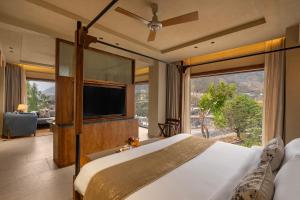 a bedroom with a large bed and a large window at Auradoon, Dehradun - By Leisure Hotels in Dehradun