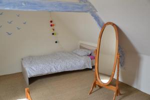 een kleine slaapkamer met een spiegel en een bed bij Petit Paris in Kergrist