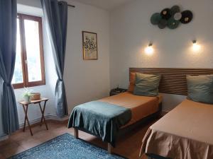 a bedroom with two beds and a window at Auberge La Tournelle in Saint-Jean-de-Valériscle