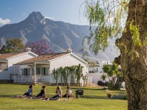 a group of people sitting on the grass in front of a house at Boho Club in Marbella