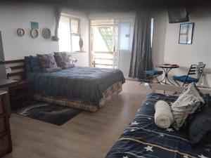 a bedroom with a bed and a couch and a table at Ryans Surf Cabin in Jeffreys Bay