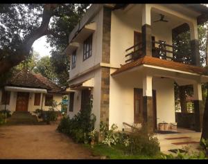 a large white house with a tree in front of it at ABRU'S Holidays International Travelers in Alleppey