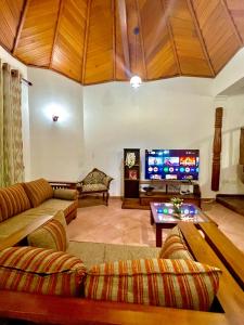 a living room with couches and a large screen tv at Gemlita Villa in Uswetakeiyawa in Bopitiya