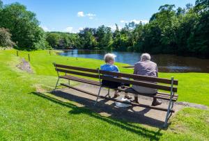 an older couple sitting on a park bench near a river at Holiday Home by the river Nidd 4 in Knaresborough