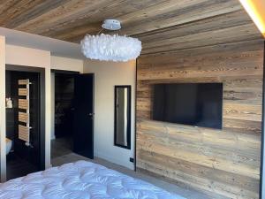 a bedroom with a wooden wall with a flat screen tv at Somptueux chalet in Megève +11 photos