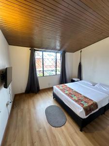 Un dormitorio con una cama y una ventana grande. en Bamuka Hostal, en Bogotá