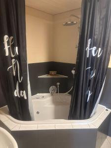 a bathroom with a tub with a black shower curtain at Ferienwohnung Klosterblick in Bastheim +17 photos