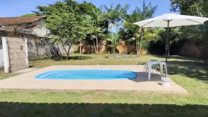 a swimming pool with an umbrella and a chair at Praia do Paraíso in Mosqueiro