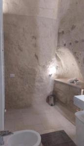 a stone bathroom with a toilet and a sink at Radici Cave & Suite in Matera +44 photos