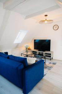 a living room with a blue couch and a tv at Sewwa Guest House in Sélestat